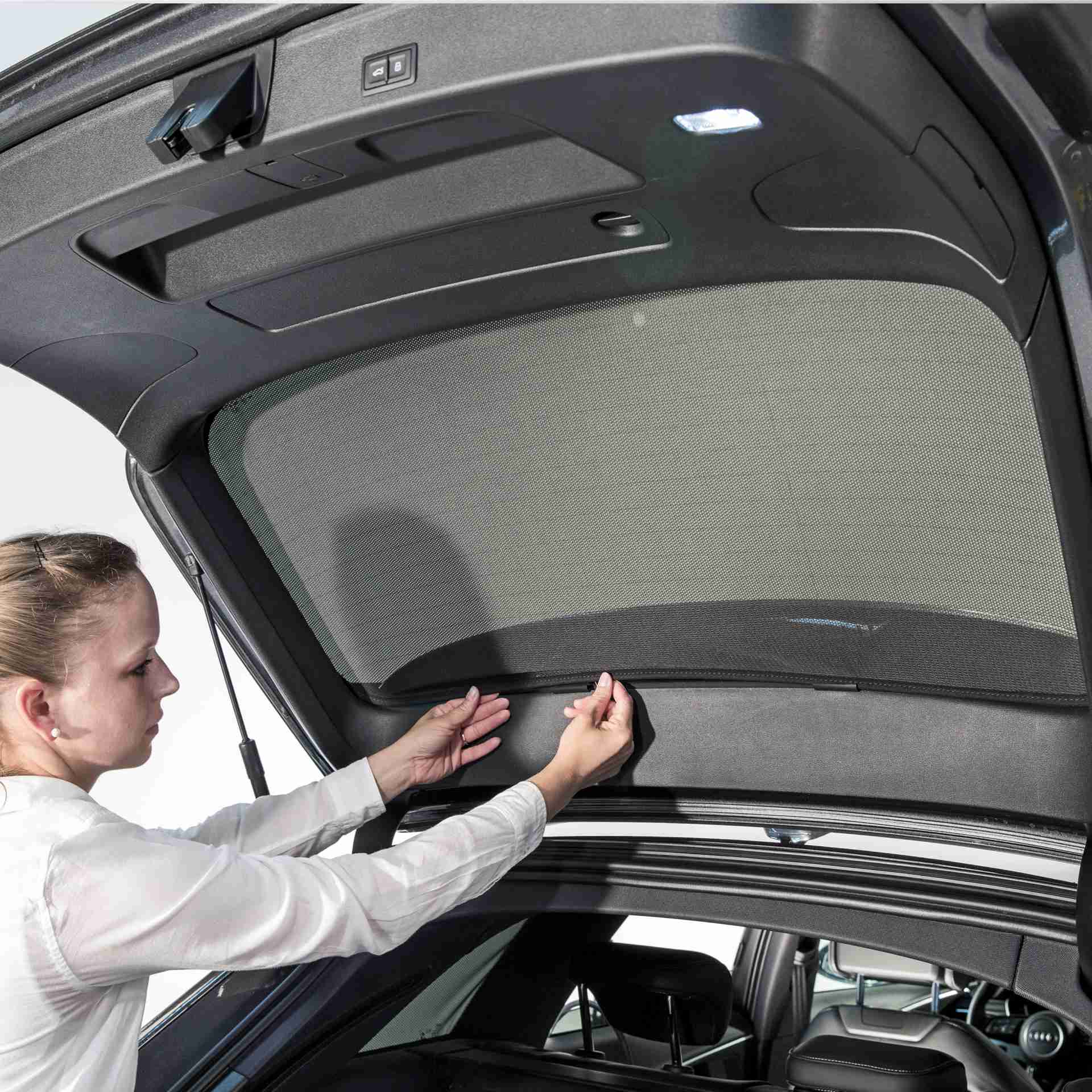 a woman installs a sunclip to the rear window of a car