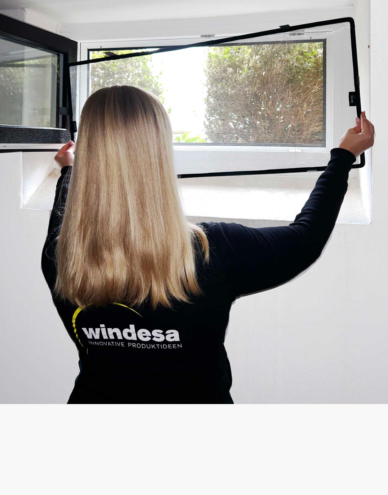 eine Frau hält den WinClip Kellerschutz an ein Kellerfenster