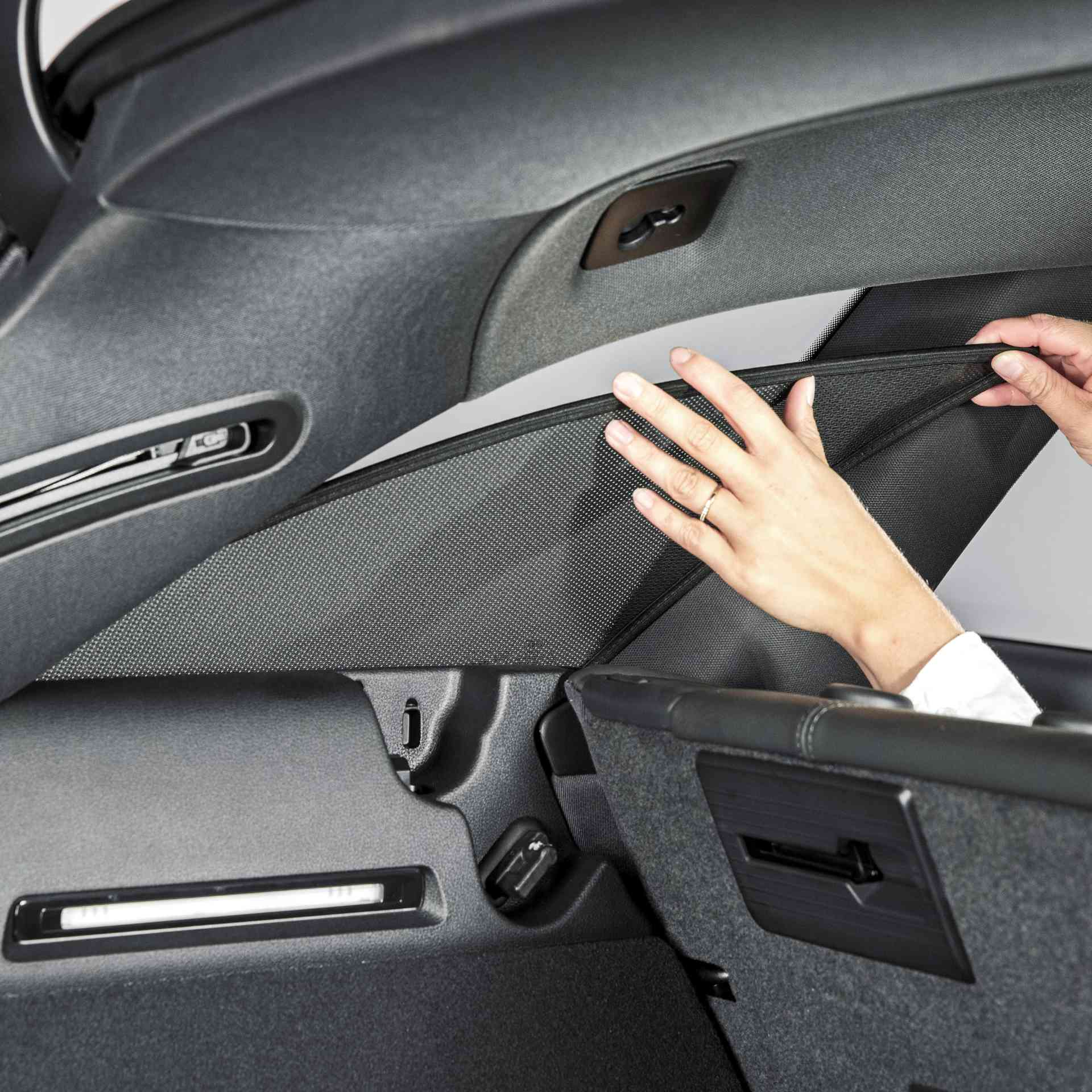 jemand bringt eine Sonnenblende an die hintere Autoscheibe an