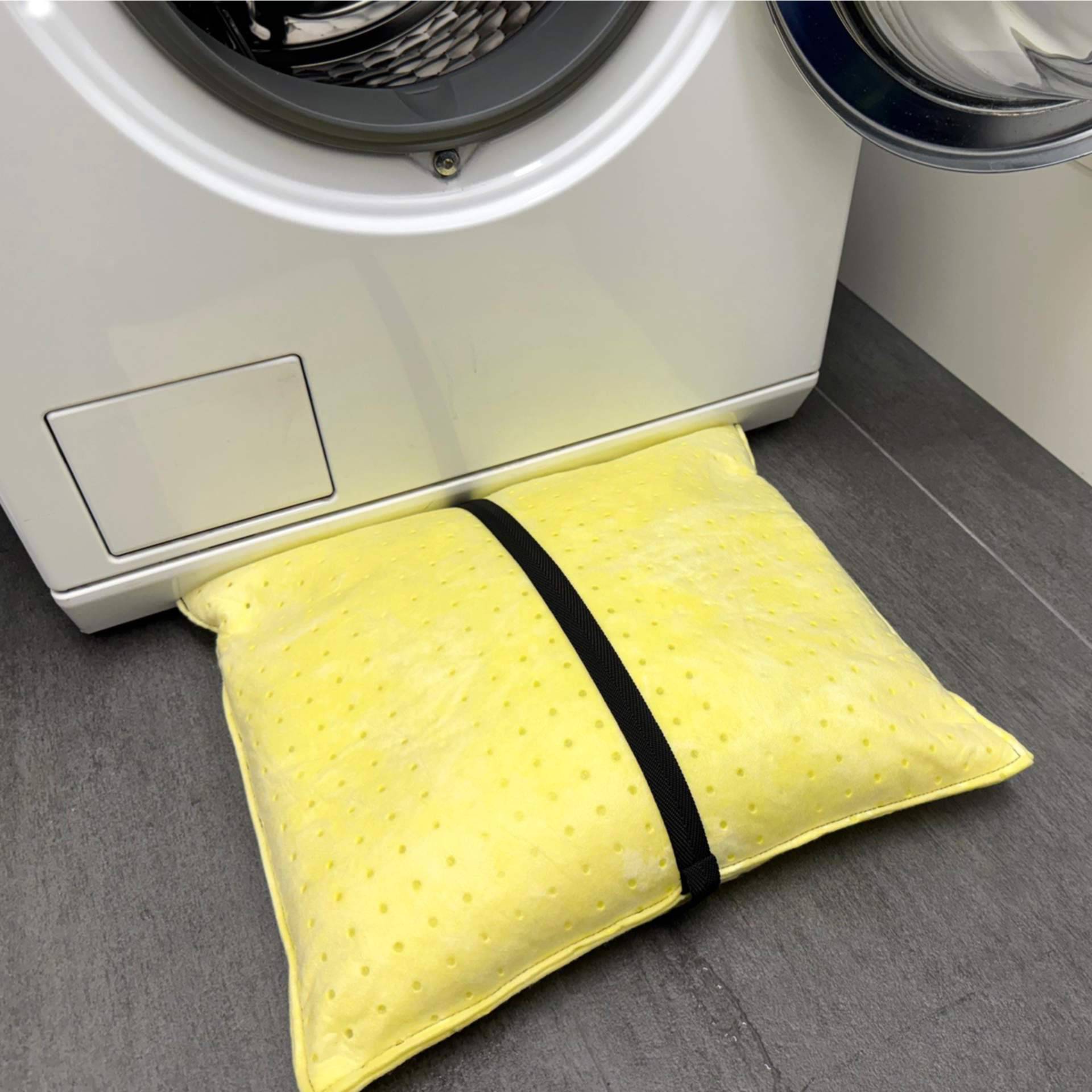 ein Wasserschutzkissen liegt vollgesogen vor einer auslaufenden Waschmaschine