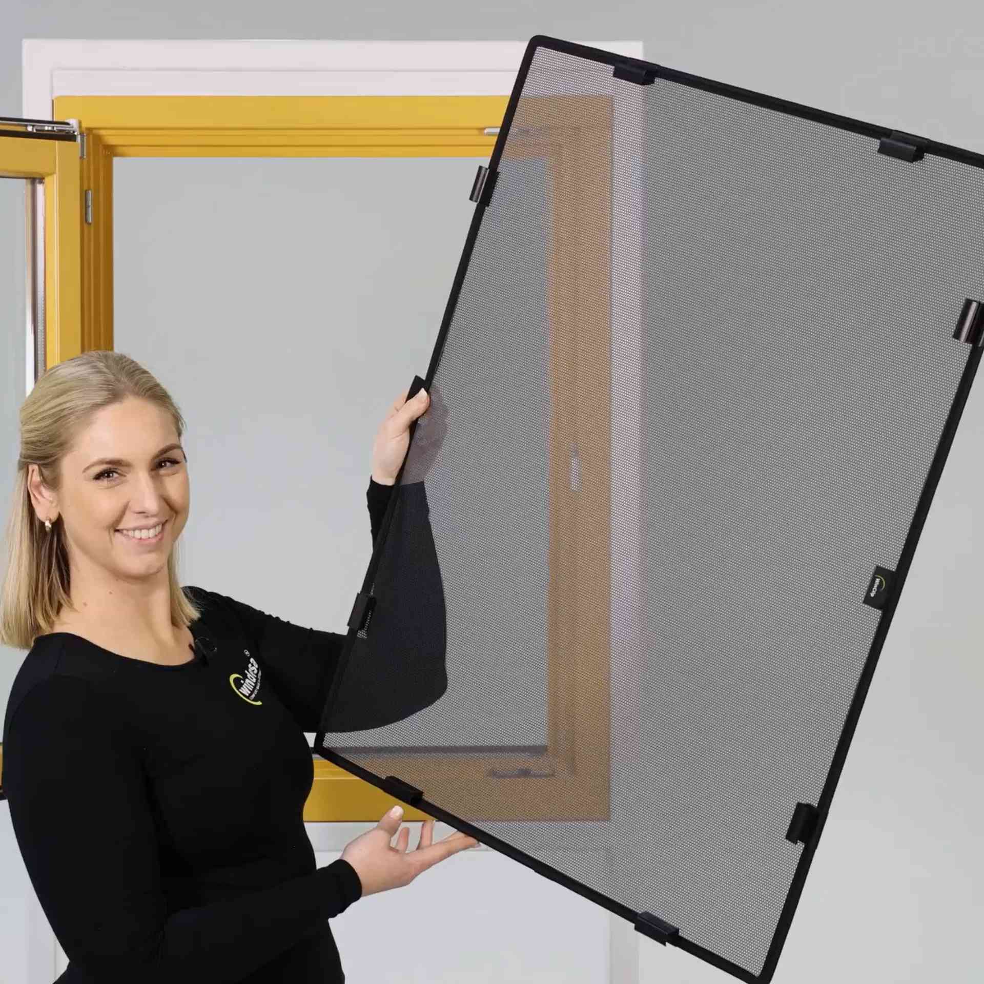 eine Frau hält den WinClip Multi lächelnd vor einem Holzfenster