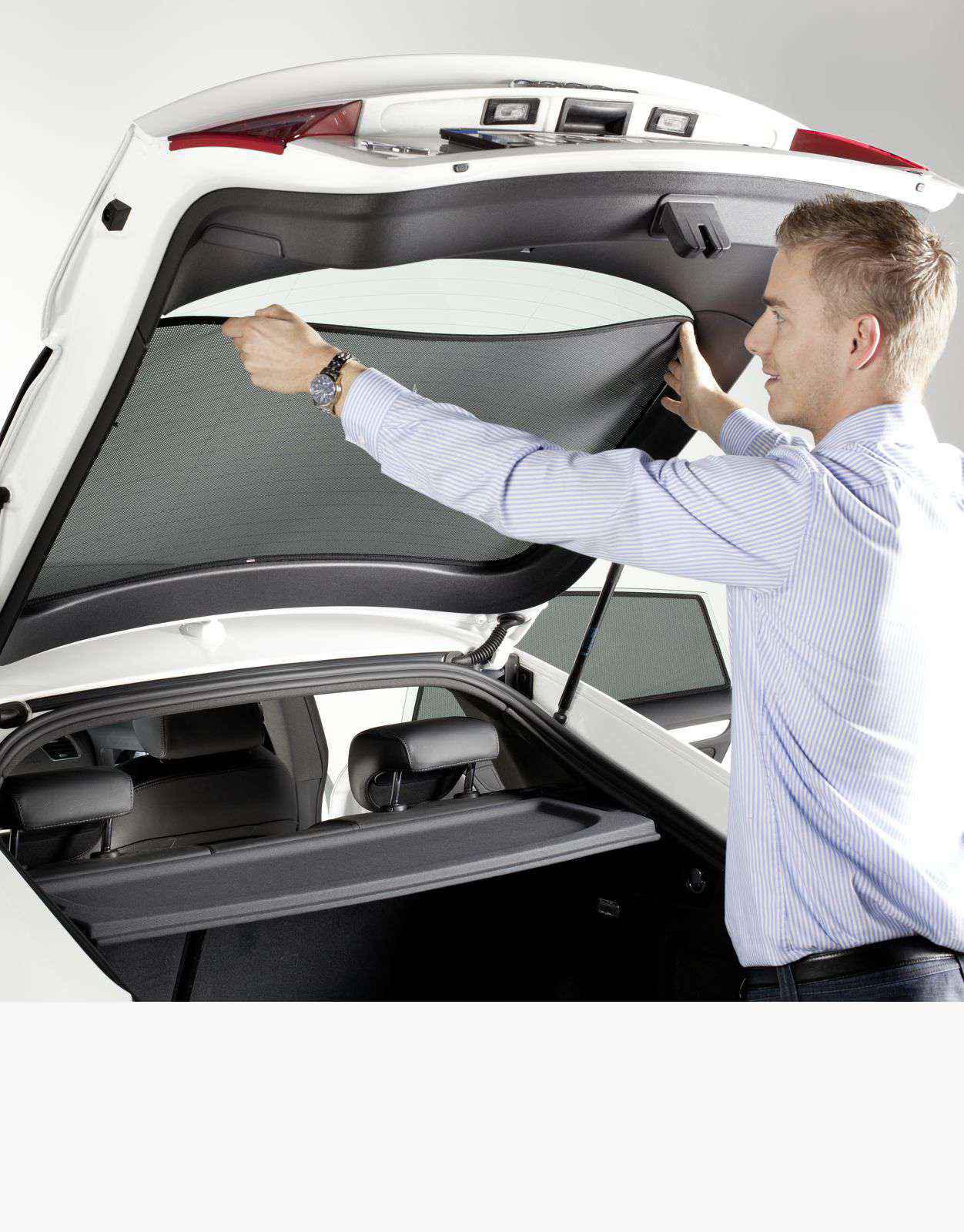 ein Mann bringt einen Sonnenschutz an die Heckscheibe an
